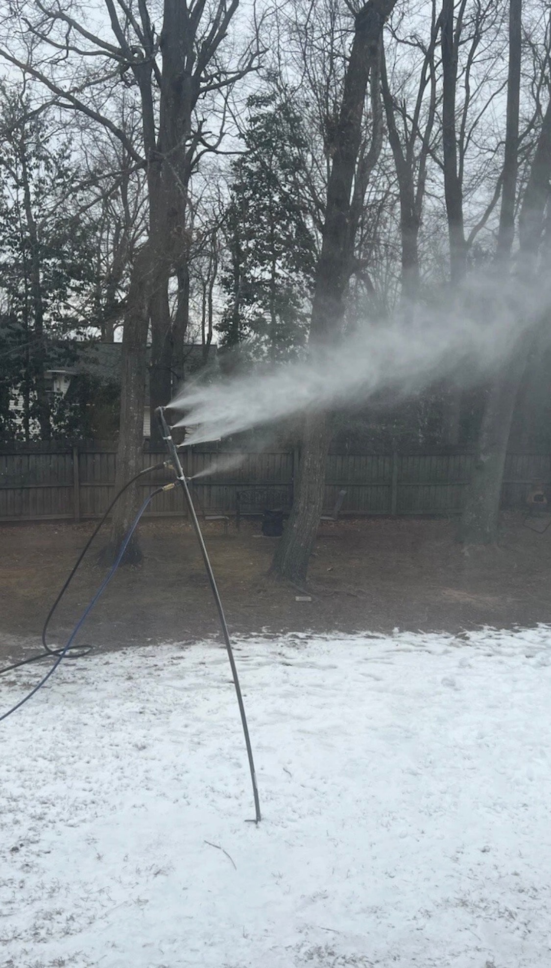 Four-nozzle snowmaker blasting snow in a suburban backyard