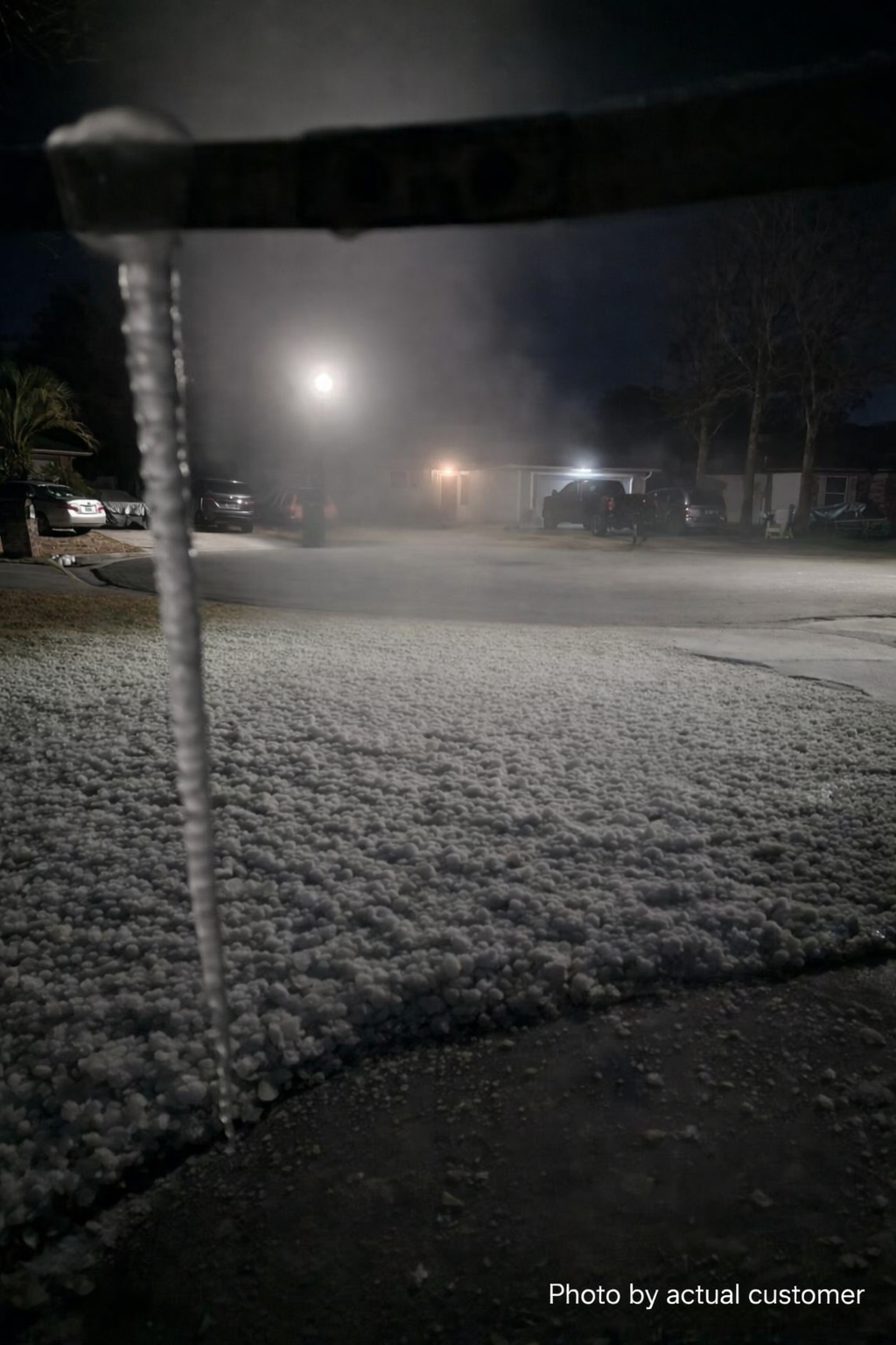 Icicle forming on a nozzle with snow-covered ground at night