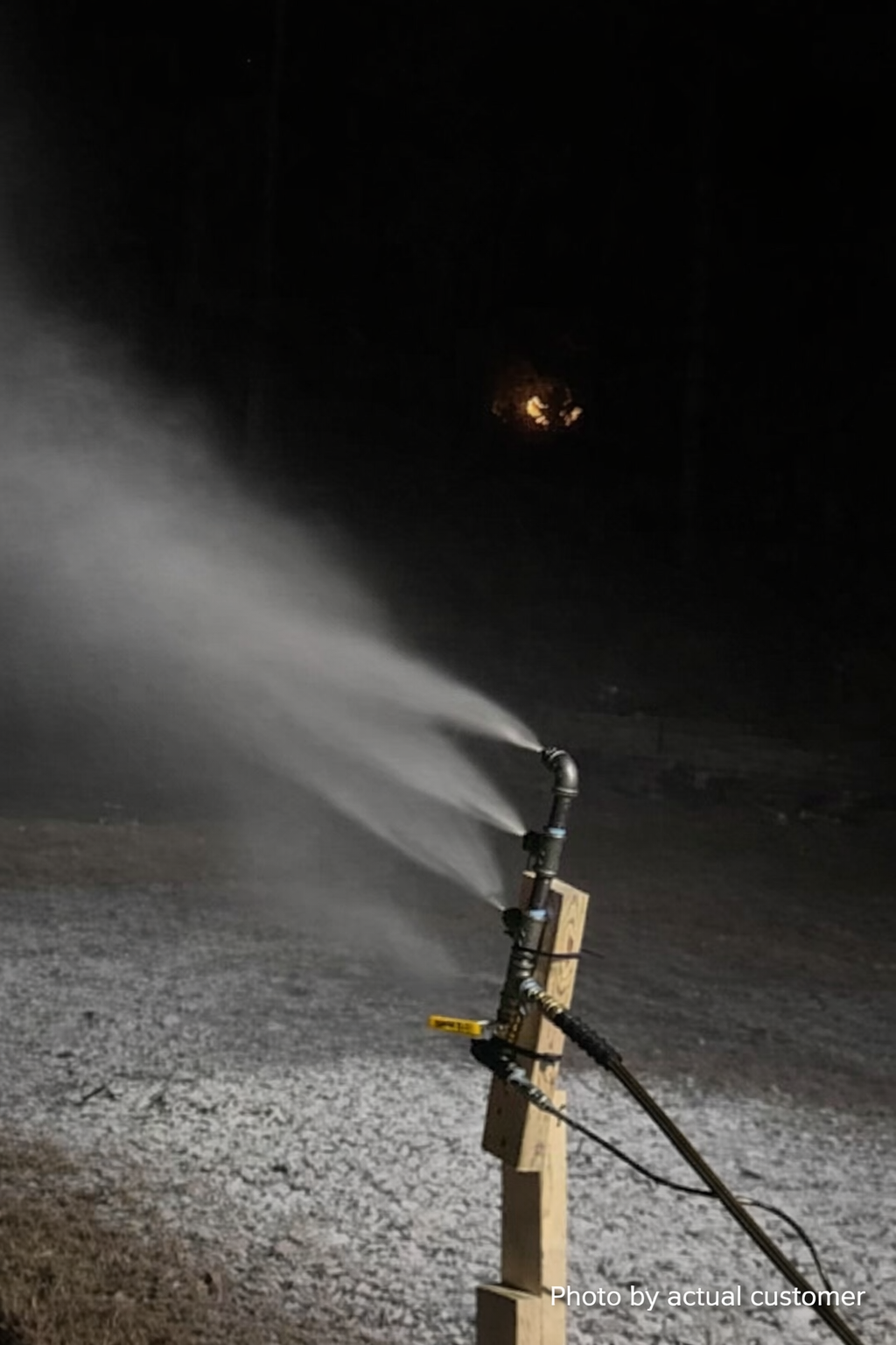 Snowmaker spraying water mist across yard at night